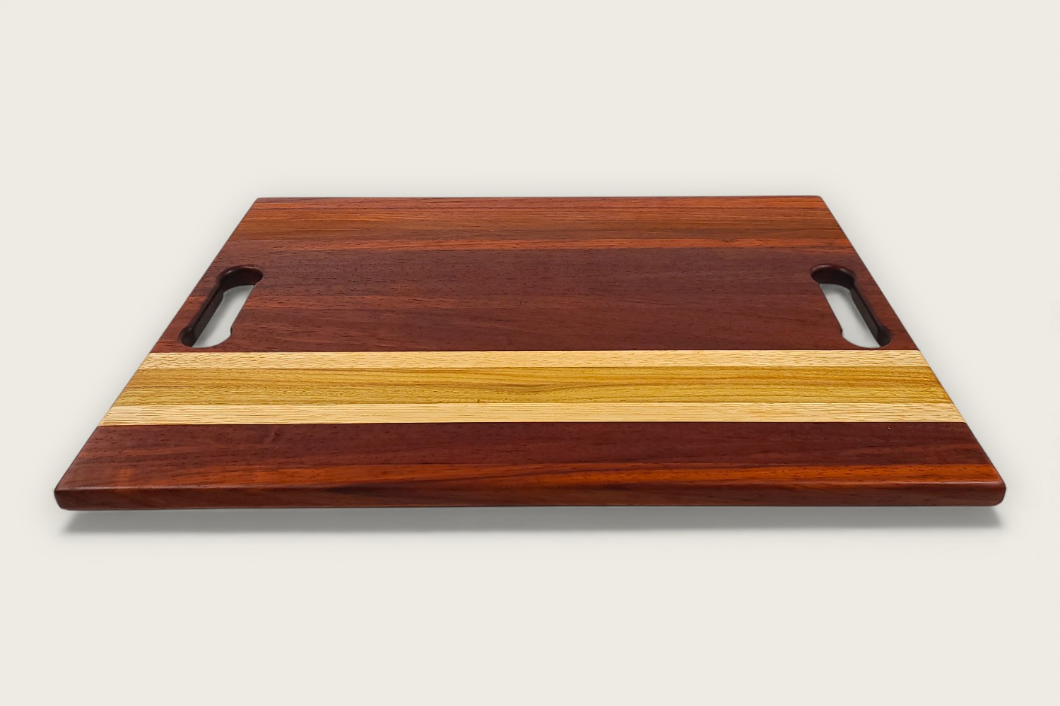 Padauk Pro Series cutting board with bold reddish tones, edge-grain pattern, rectangular shape, and tung oil finish.