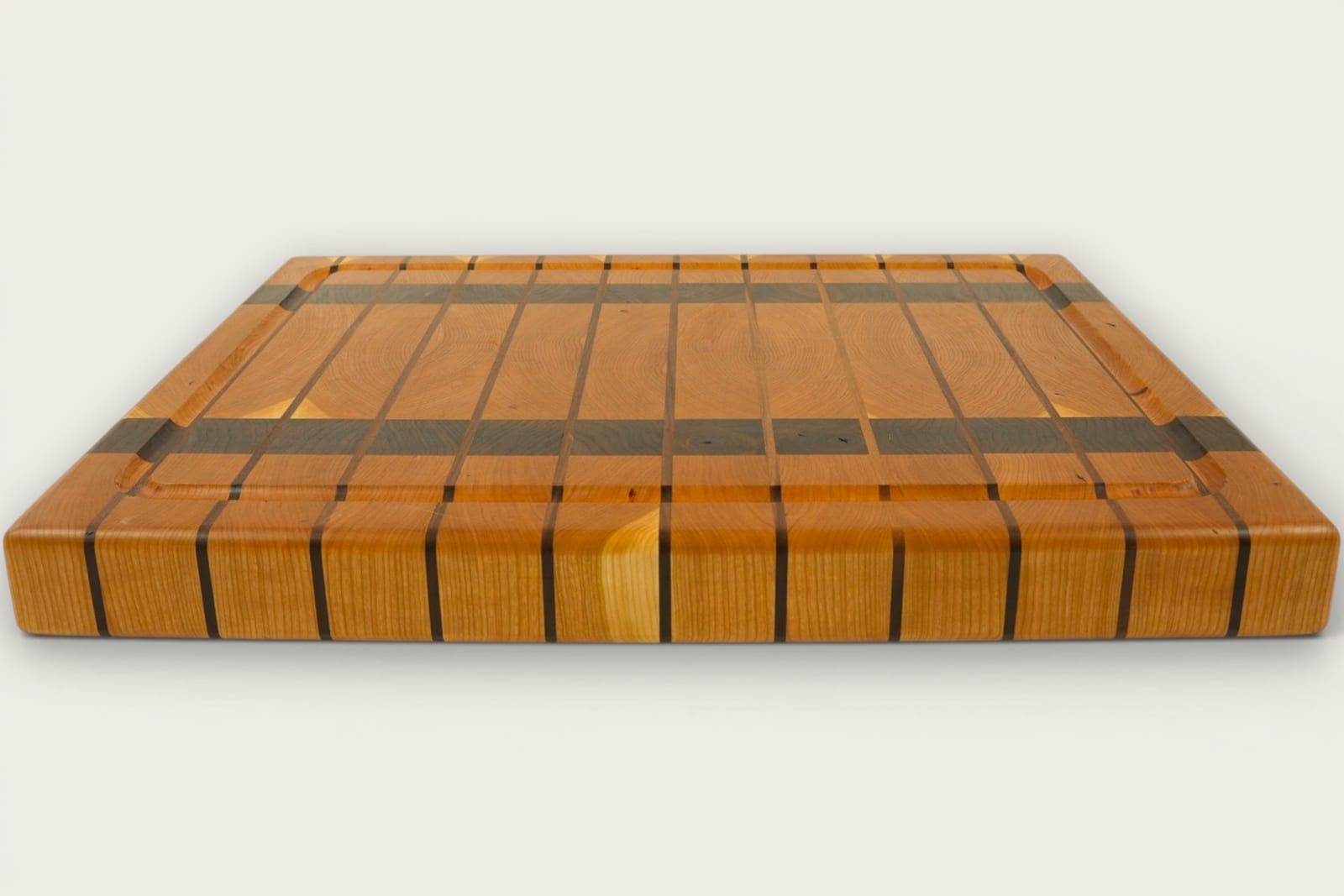 Cherry and walnut chopping block with vertical end-grain pattern, warm amber tones, and recessed handles.